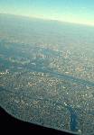飛行機から東京を見下ろす。ずっと向こうに見える「白いポチ」は富士山